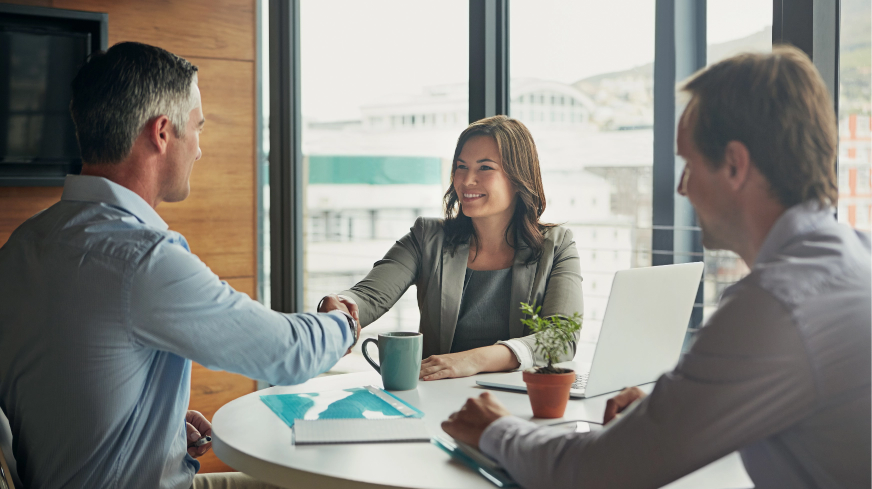 A meeting is shown with a client shaking the hand of an agent