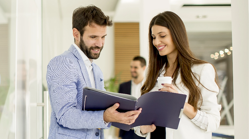 A client looks through a notebook of information presented to them by an agent