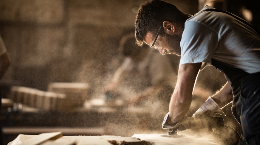 A carpenter sands wood with a power tool